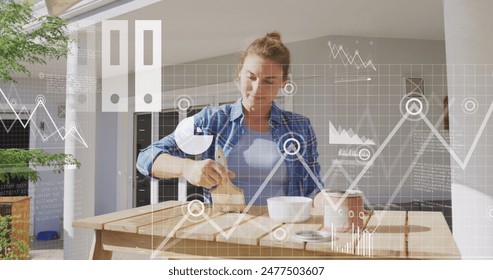 Image of multiple icons, graphs, map, caucasian woman painting wooden table at home. Digital composite, multiple exposure, report, database, business, restoring and global concept. - Powered by Shutterstock