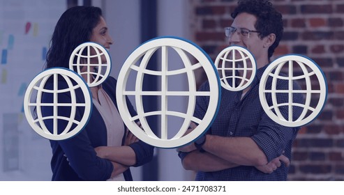 Image of multiple web globe icons floating against diverse man and woman smiling at office. Global networking and business technology concept