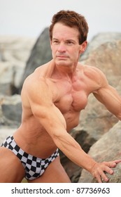 Image of a muscular man posing on the rocks