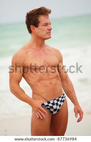 Image of a muscular man posing on the beach