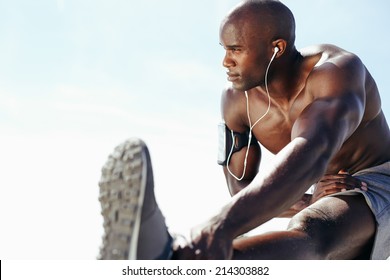 Image of muscular young man working out against sky. African man looking away with stretching his leg. Shirtless male model exercising outdoors. - Powered by Shutterstock