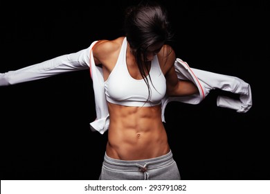Image of muscular young woman wearing sports jacket. Getting ready for workout on black background