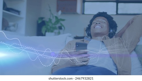 Image of music data processing over african american man with headphones. Music, entertainment, computing and data processing concept digitally generated image.