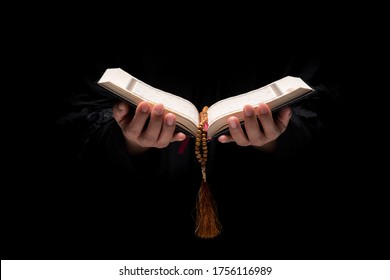 The image of a Muslim woman's hand, Islamic prayer, and her hand holding a quran and rosary beads or tasbih. Arabic word translation : The Holy Al Quran (holy book of Muslim) - Powered by Shutterstock