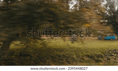 Image of nature in the countryside. An old car driving along a picturesque road. Autumn landscape of yellow-green trees. Traveling to beautiful corners of the world. Can be used as banner background