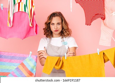 Image Of Negative Displeased Sad Woman Housewife Isolated Over Pink Wall Background Dry Clothes On Rope.