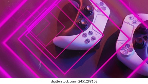 Image of neon light trails over image game computer pads. Global image game, digital interface, data processing and connections concept digitally generated image.