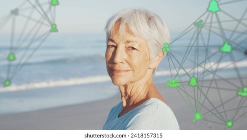 Image of network of connections with icons over smiling senior woman on beach. digital interface, social media and global technology concept digitally generated image. - Powered by Shutterstock