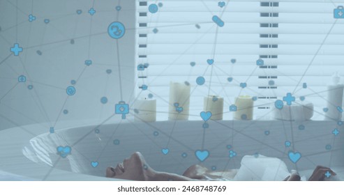 Image of network of digital icons over biracial woman relaxing in a bathtub in bathroom. Global networking and technology concept - Powered by Shutterstock