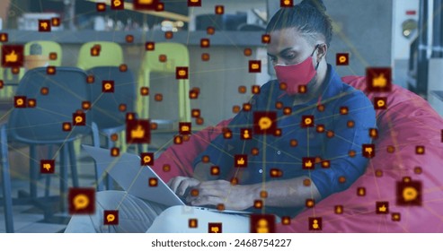 Image of network of digital icons over biracial man wearing face mask using laptop at office. Global networking and covid-19 pandemic concept - Powered by Shutterstock