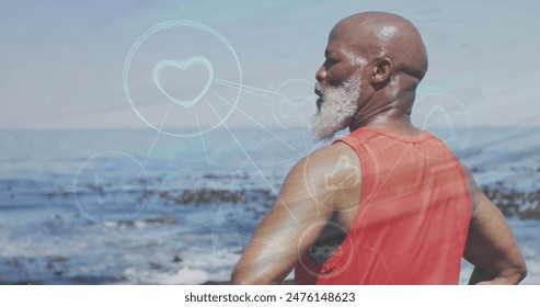Image of network of digital icons over african american senior man standing near the sea. Sports and fitness technology concept - Powered by Shutterstock