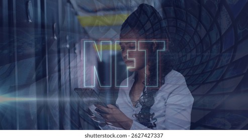 Image of nft text over african american using tablet in server room. Cloud computing, digital interface and security concept digitally generated image.