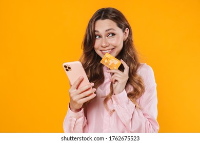 Image Of Nice Pleased Woman Holding Credit Card And Mobile Phone Isolated Over Yellow Background