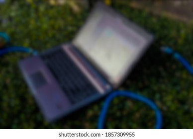 Blurred​ Image, notebook computer resting on​ the​ grass​