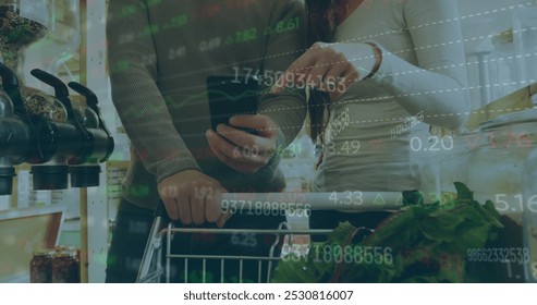 Image of numbers changing and data processing over people with shopping trolley using smartphone. global business and finance concept digitally generated image.