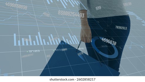 Image of numbers changing and data processing over woman holding blue shopping bag. global business and finance concept digitally generated image.