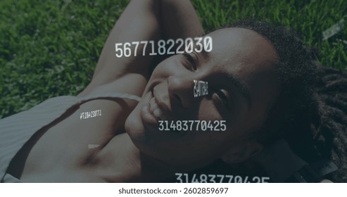 Image of numbers processing over happy woman lying on grass. digital interface global networking connection and communication concept digitally generated image.