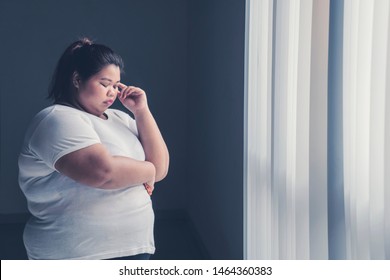 Image Of Obese Woman Thinking Something While Standing Near The Window 