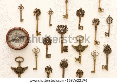 Image of old antique keys and compass over wooden background. Top view, flat lay