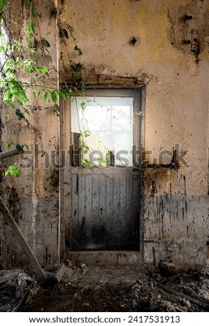 An image of an old building in a state of disrepair, featuring a worn-out door and a shattered window.