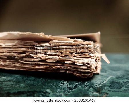 Image of old tattered worn rough papers in a book or as a packet of documents textured and stained with age