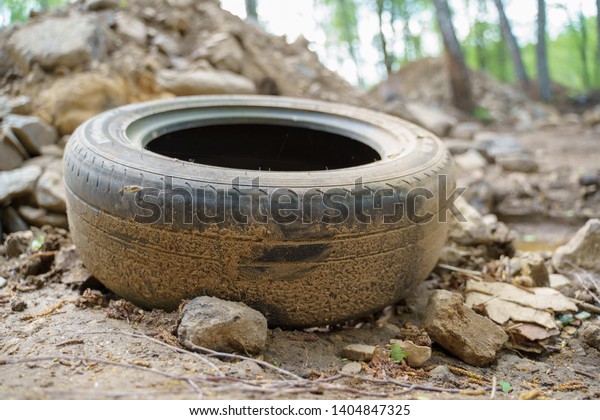Image of old tires\
from car on road in woods