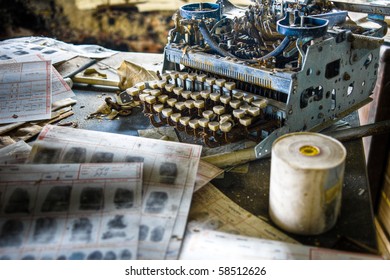 Image Of An Old, Vintage Rusty Typewriter In A Derelict Abandoned Police Station With Criminal Fingerprint Files Scattered On The Desk.