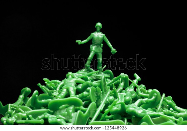 Image of one soldier standing over the dead plastic toy soldier against the dark background