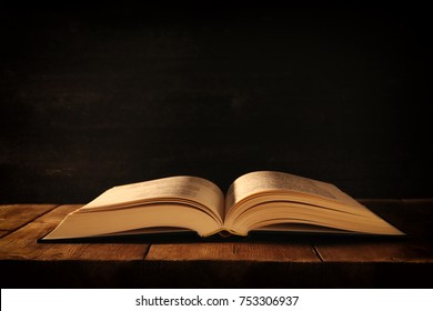 Image Of Open Antique Book On Wooden Table.