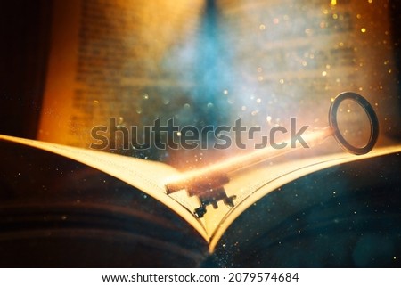 image of open antique book on wooden table with vintage key