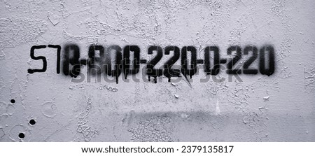 Image of a paint-covered gray metal sign with cracks and stenciled number.