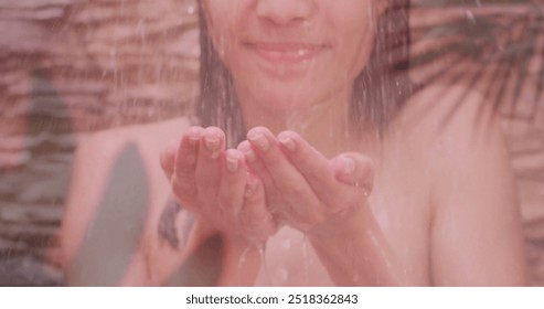 Image of palm leaves over happy biracial woman splashing face in shower. Nature, self care, beauty, relaxation, wellbeing and lifestyle, digitally generated image. - Powered by Shutterstock