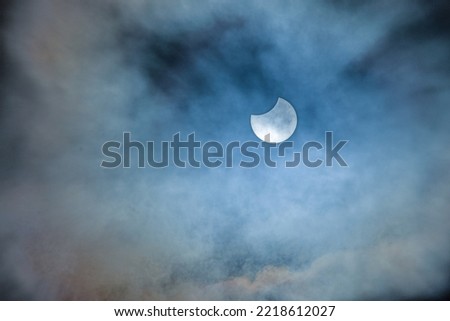 Image of a partial solar eclipse through veil clouds