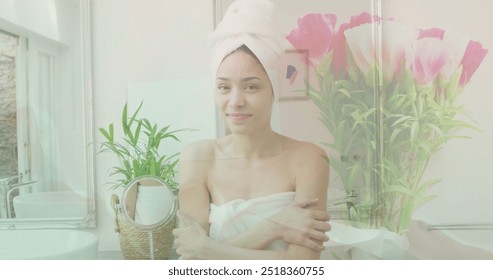 Image of pink flowers in vase over portrait of happy biracial woman wearing towel in bathroom. Nature, self care, beauty, relaxation, wellbeing and lifestyle, digitally generated image. - Powered by Shutterstock