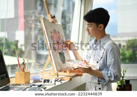 Image of pleased man artist painting picture with watercolor on canvas in art workshop. Art, creative hobby and leisure activity concept