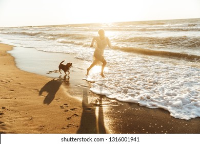 Image of pleased woman 20s running with her dog by seaside in the morning - Powered by Shutterstock