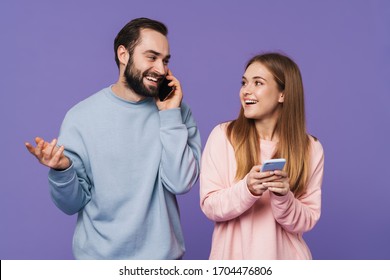 Image of positive optimistic loving couple isolated over purple background talking by mobile phones chatting. - Shutterstock ID 1704476806