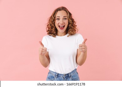 Image of a positive optimistic young pretty woman posing isolated over pink wall background showing thumbs up gesture.
