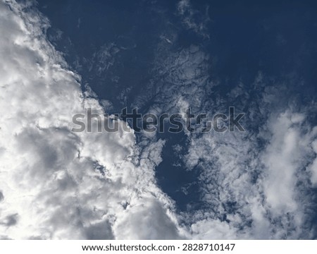 The image presents a dramatic, close-up skyward shot showing a distinct dividing line between two different cloud formations and sky conditions.

Foreground and Lower Half: Dense, thick, and billowy white-and-gray cumulus clouds occupy the lower section of the frame, showing heavy texture, depth, and shadowy highlights.

​Background and Upper Half: 
A deep navy-blue sky stretches across the top portion, covered with thin, wispy, feathered altocumulus clouds that create a sheer, textured veil over the dark backdrop.