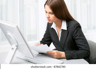 Image Of Pretty Business Woman Sitting In Front Of Computer And Looking At Its Screen