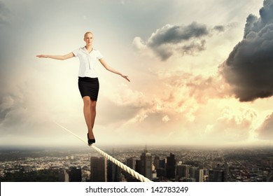 Image of pretty businesswoman balancing on rope