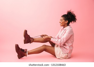 Image of a pretty happy young african woman posing isolated over pink wall background wearing shoes.