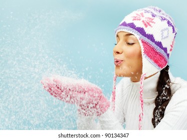 Image Of Pretty Woman In Pink Gloves And Knitted Winter Cap Blowing Snow From Her Palms