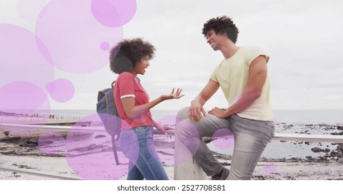 Image of purple spots over happy biracial couple talking on beach promenade. Romance, love, vacations and free time, digitally generated image. - Powered by Shutterstock