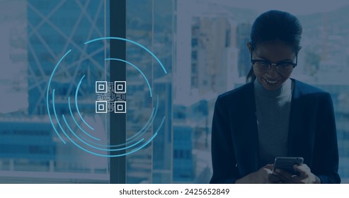Image of qr code icon over biracial businesswoman using smartphone in office. Global business and digital interface concept digitally generated image.