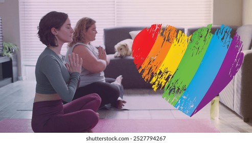 Image of rainbow heart over caucasian lesbian couple practicing yoga at home. supporting lgbt rights and gender equality digitally generated image. - Powered by Shutterstock