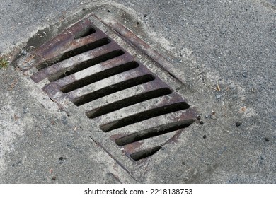 An Image Of A Rectangular Shaped Storm Drain Cover On A Paved Street.