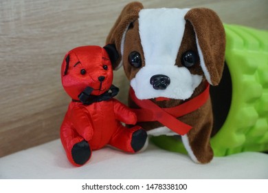 Image Of Red Bear Doll And Brown Dog Doll With Red Neck Tie Close Together With Green Foam Roller On The White Pillow And Wooden Background