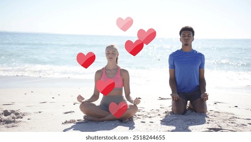 Image of red hearts over diverse couple meditating on beach. Summer, vacation, lifestyle and digital interface concept digitally generated image. - Powered by Shutterstock