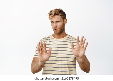 Image Of Reluctant Handsome Man Shaking Hands In Rejection Gesture, Saying No, Decline Offer, Standing Over White Background